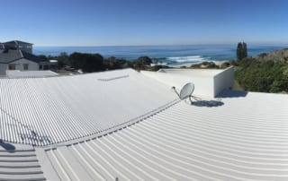 Dish Antenna on the White Roof with the Ocean view and Green Trees in the Background