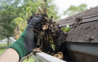 Gloved hand removing dirt from guttering