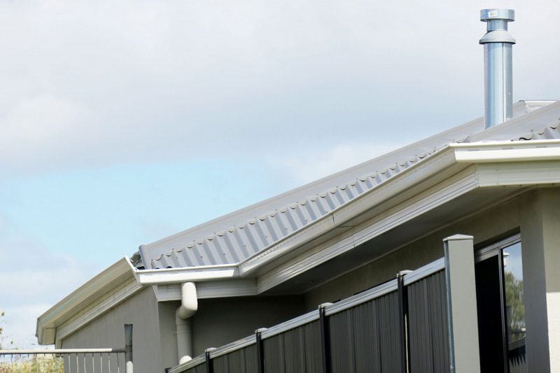 A section of roof with a chimney and gutter.