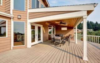 A wooden deck with a table and chairs underneath a flat roof extension.