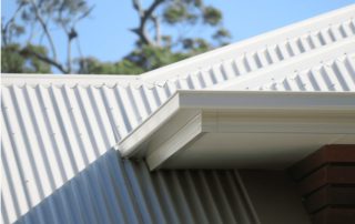 House with white roofline and trees in background